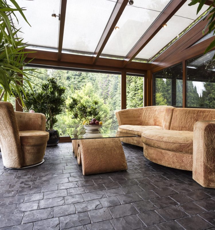 Comfortable plush lounge set in a conservatory with dark stone floor
